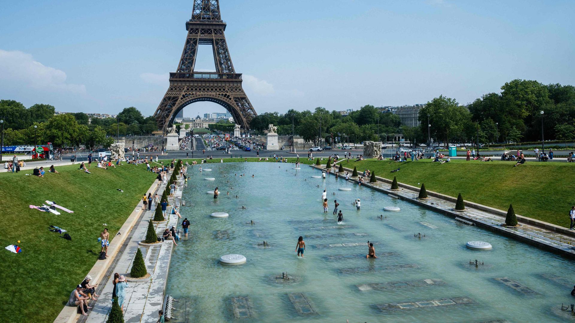 Menschen kühlen sich im Trocadero-Brunnen in Paris mit Blick auf den Eiffelturm ab. 