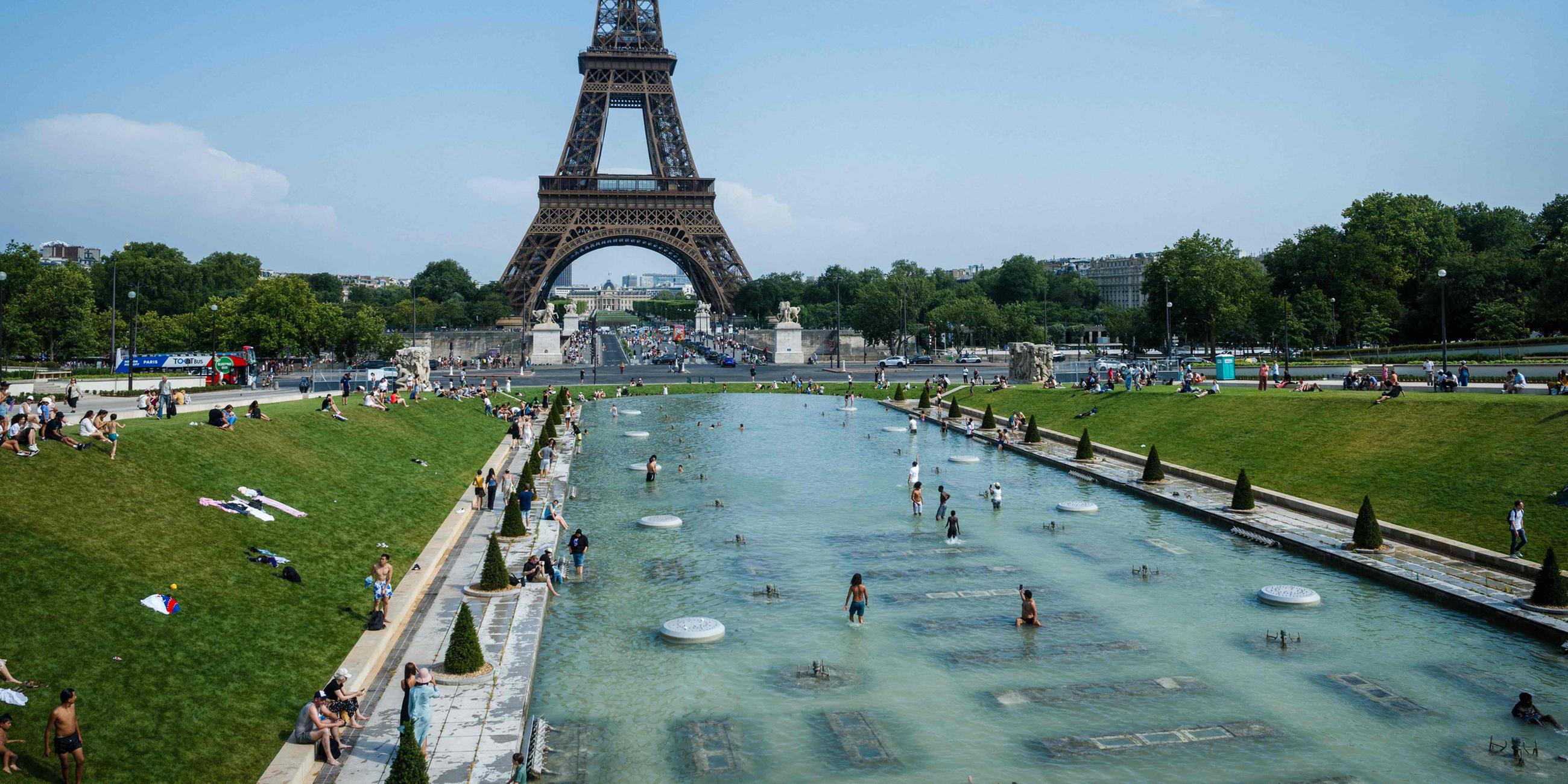 Menschen kühlen sich im Trocadero-Brunnen in Paris mit Blick auf den Eiffelturm ab. 