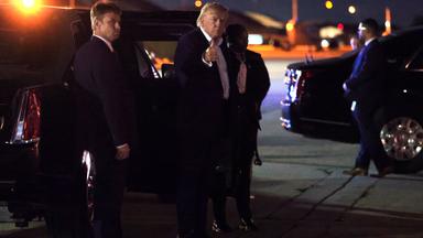 Donald Trump steht im Dunkeln auf einem Rollfeld und zeigt den Daumen hoch in Richtung Kamera.