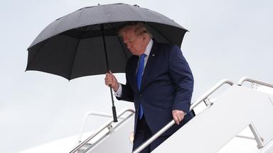 US-Präsident Trump steigt mit einem Regenschirm aus der Air Force One aus.