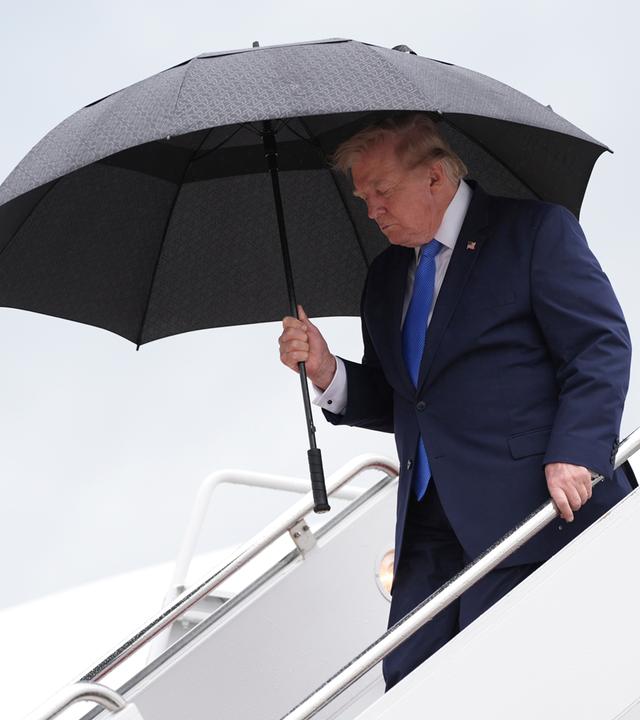 US-Präsident Trump steigt mit einem Regenschirm aus der Air Force One aus.