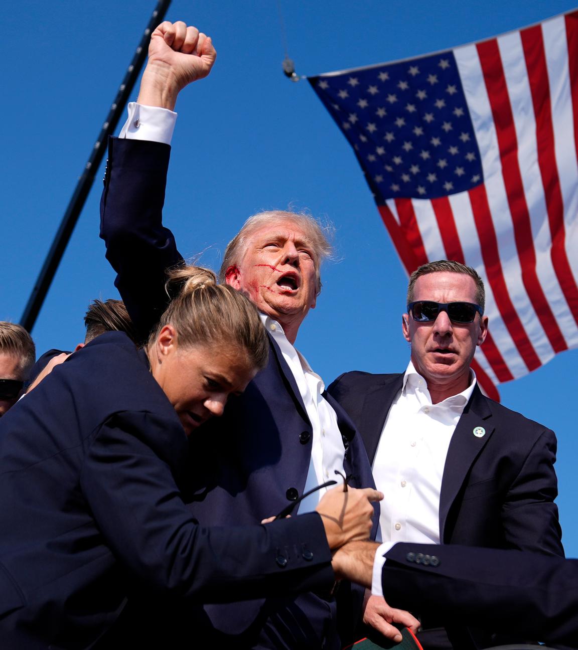 Donald Trump reckt blutverschmiert seine Faust in die Höhe, umgeben von Personenschützern