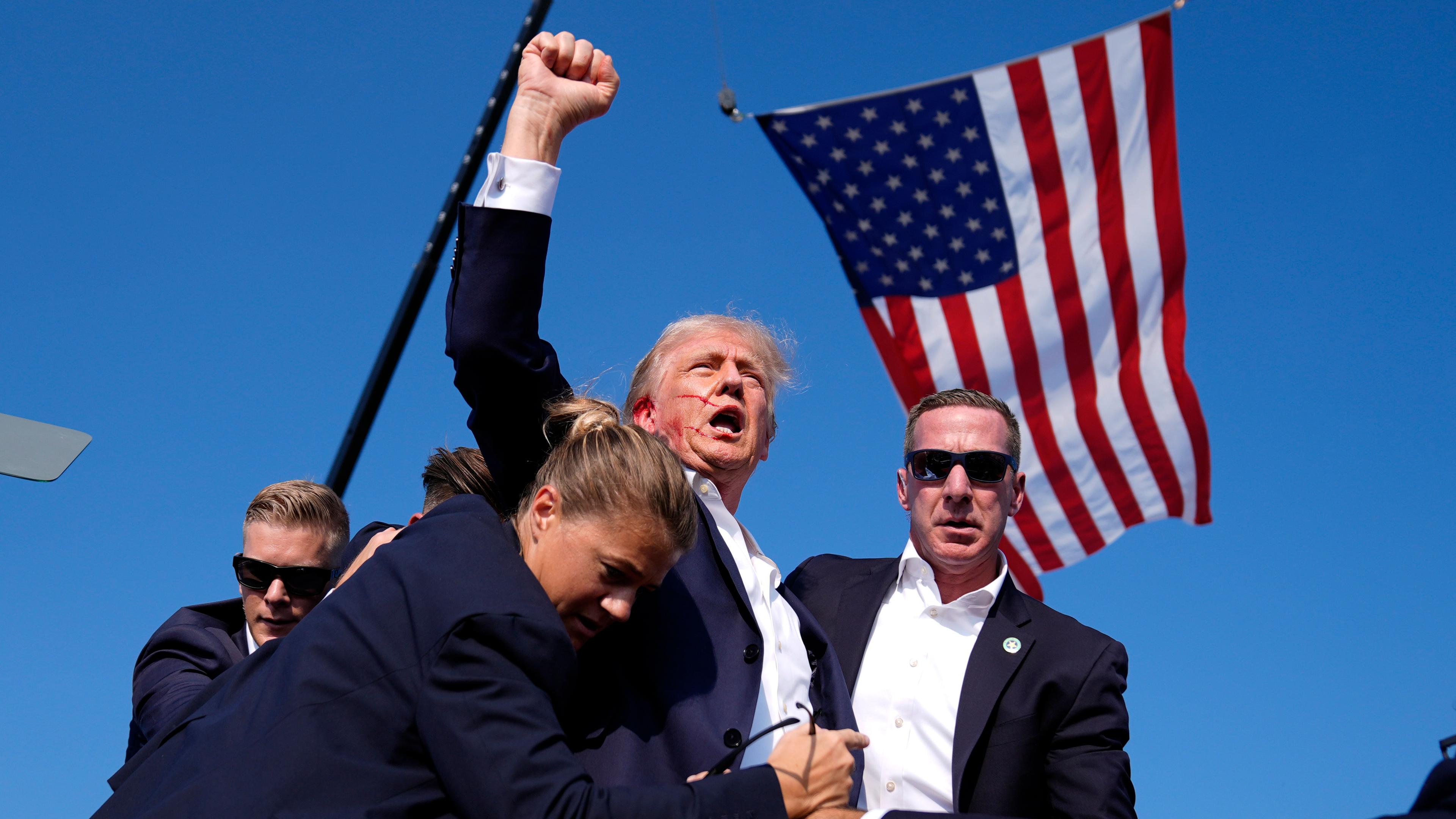 Donald Trump reckt blutverschmiert seine Faust in die Höhe, umgeben von Personenschützern