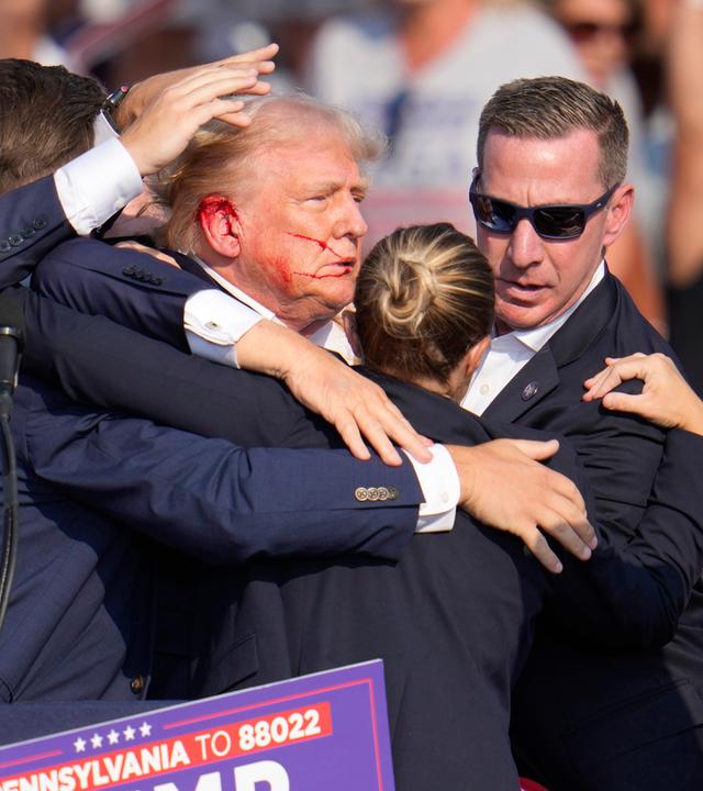 Der republikanische Präsidentschaftsbewerber und frühere US-Präsident Donald Trump wird nach einem Attentatsversuch von Agenten des US-Geheimdienstes Secret Service umringt.
