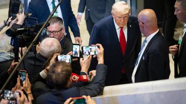 President Donald Trump leaves a plenary session in the Congress Hall, walking past journalists after his speech.
