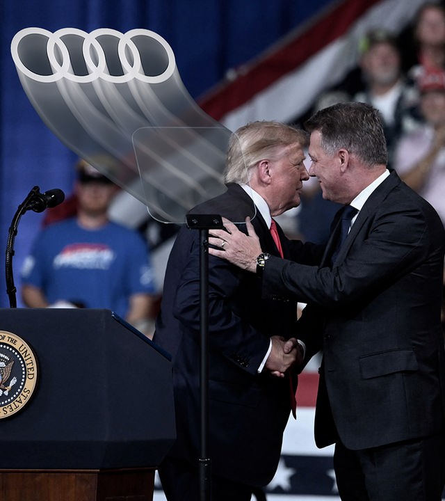 Links sind die typischen vier Audi-Ringe zu sehen. Rechts umarmen sich Donald Trump und Audi-Chef Gernot Döllner.