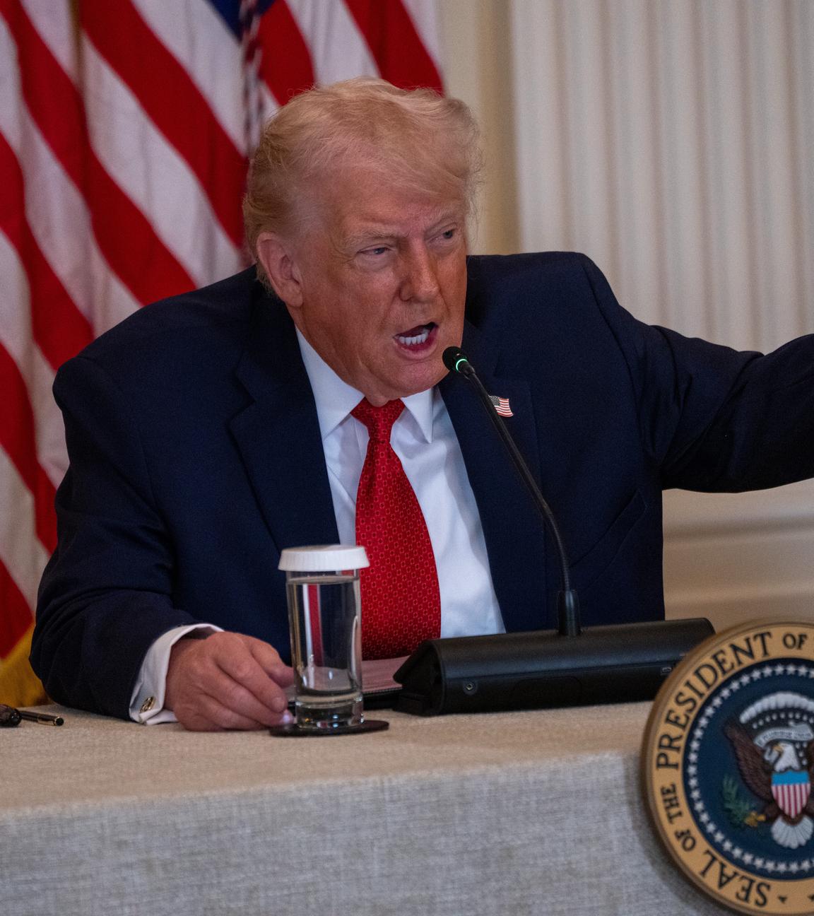 Trump sitzt am Rednerpult und gestikuliert stark