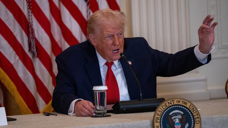 Trump sitzt am Rednerpult und gestikuliert stark