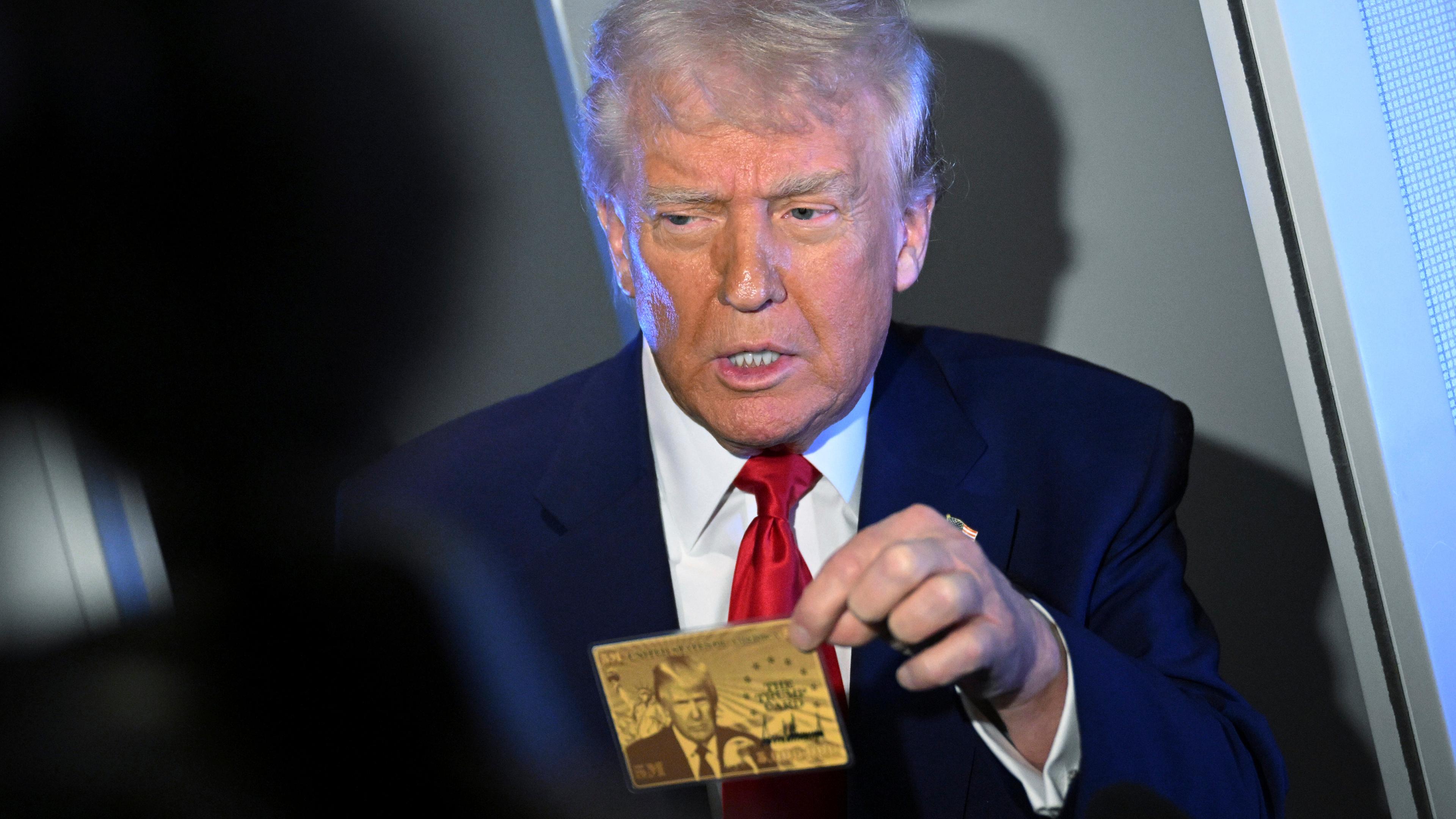Präsident Donald Trump hält die 5-Millionen-Dollar-Goldkarte hoch, während er an Bord der Air Force One mit Reportern spricht