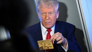 Präsident Donald Trump hält die 5-Millionen-Dollar-Goldkarte hoch, während er an Bord der Air Force One mit Reportern spricht