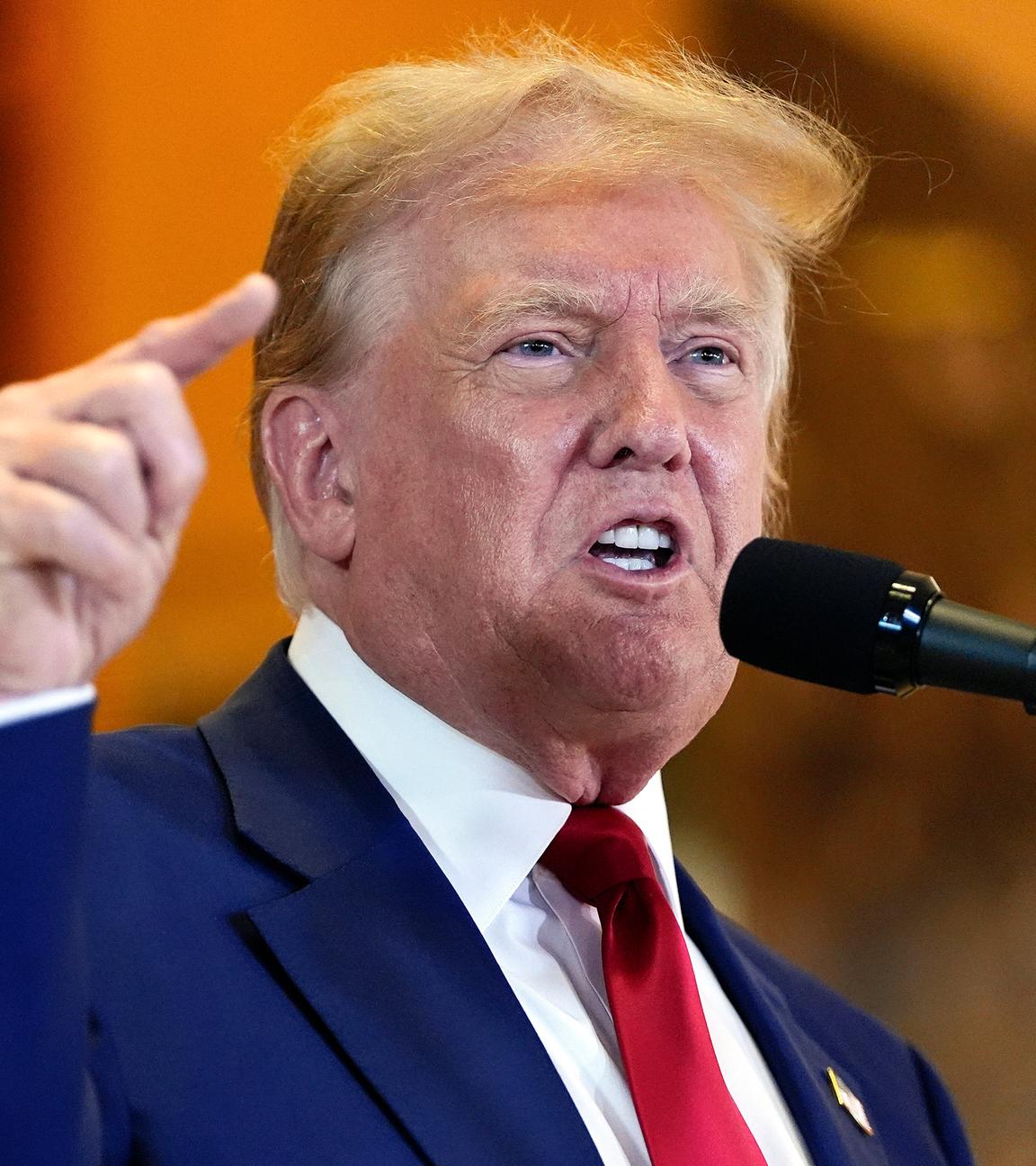 Donald Trump steht vor einem Mikro.