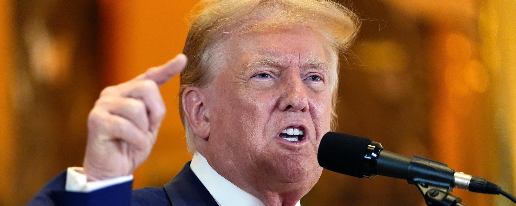 Donald Trump steht vor einem Mikro.