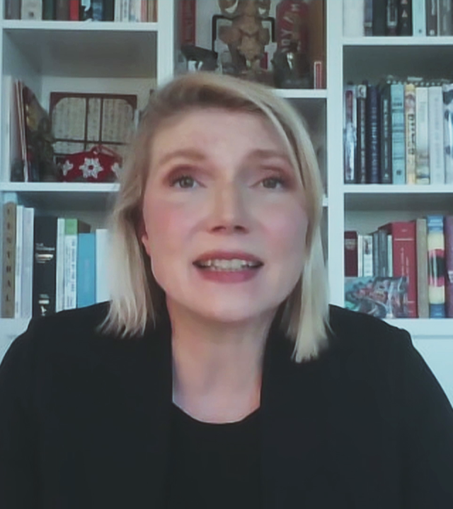 Politologin Cathryn Clüver Ashbrook vor einem weißen Bücherregal.