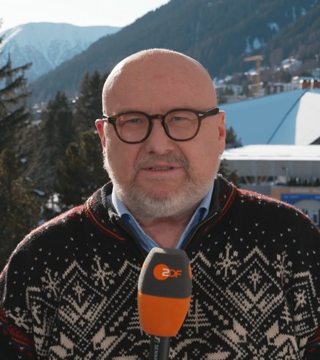 Ulf Röller im Vordergrund, im Hintergrund Berg und der Innenstadt von Davos in der Schweiz.