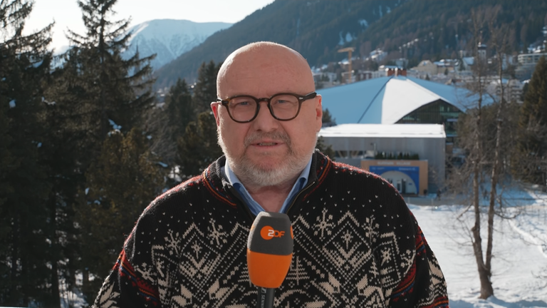 Ulf Röller im Vordergrund, im Hintergrund Berg und der Innenstadt von Davos in der Schweiz.