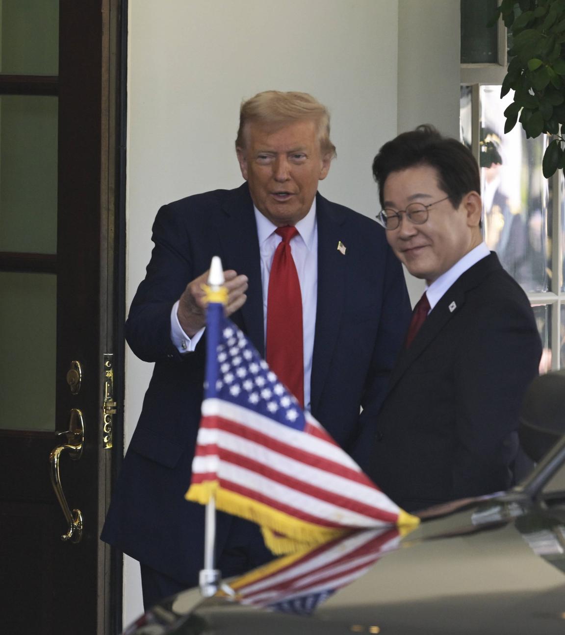 US-Präsident Trump und Südkoread Präsident Lee sprechen miteinander. Dabei ist sowohl eine US-Flagge, als auch eine Südkorea-Flagge zu sehen.