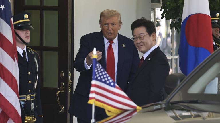 US-Präsident Trump und Südkoread Präsident Lee sprechen miteinander. Dabei ist sowohl eine US-Flagge, als auch eine Südkorea-Flagge zu sehen.