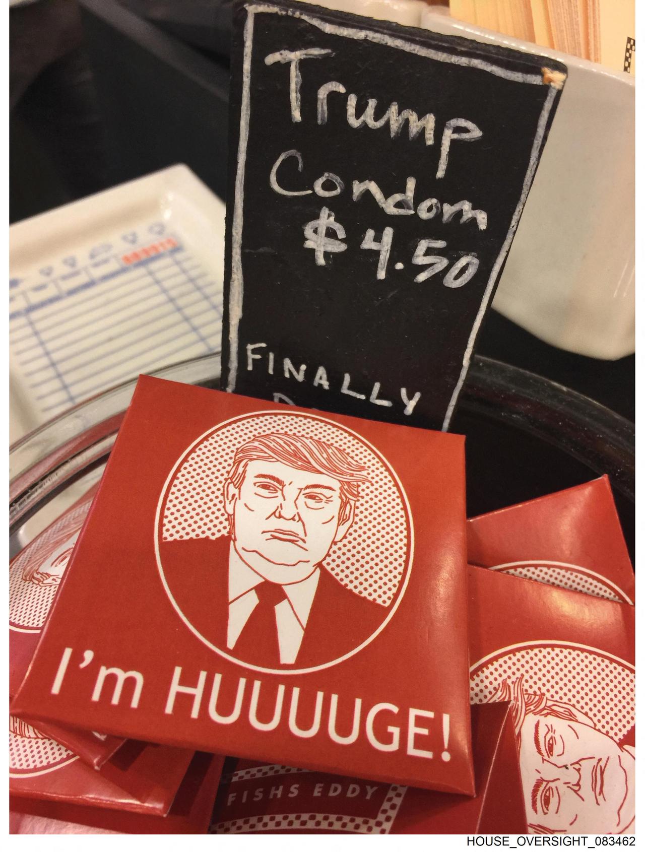 Auf einem Schild steht Trump Condom $4,50 und darunter ist eine Packung mit einer Abbildung von Trump auf der steht "I'm HUUUUGE!" 