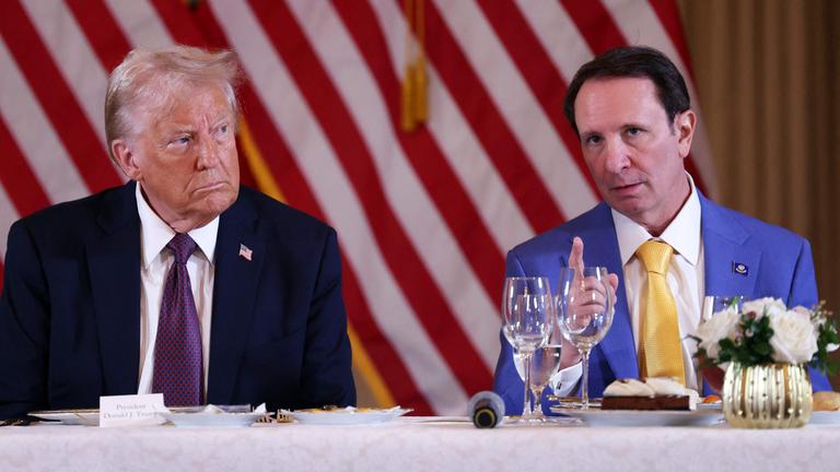 Donald Trump sitzt mit ernster Miene neben Jeff Landry.