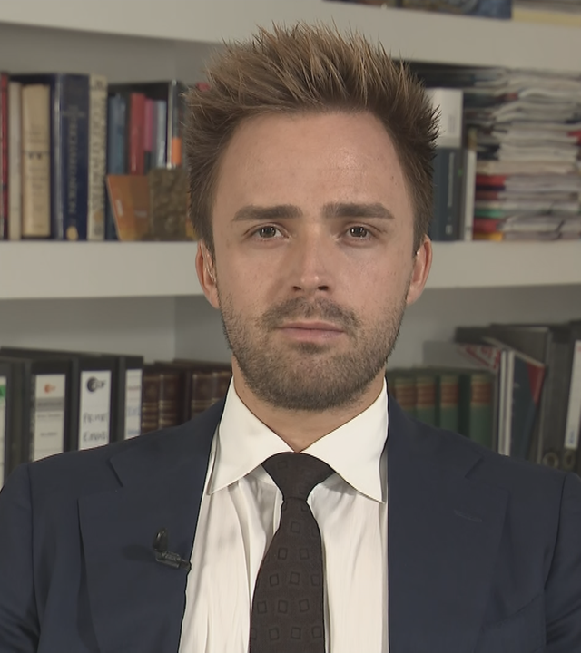 Politikwissenschaftler Julian Müller-Kaler in einem Anzug. Hinter ihm ein gefülltes Bücherregal.