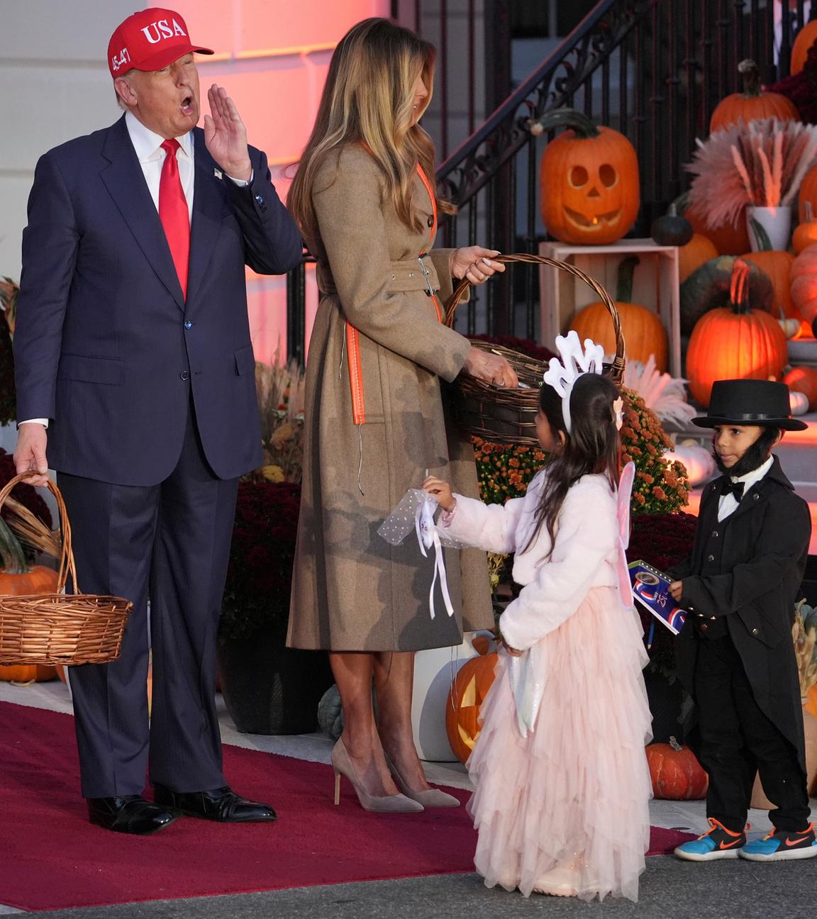 US-Präsident Donald Trump und First Lady Melania Trump verteilen Süßigkeiten an Kinder, die als Zahnfee und Abraham Lincoln verkleidet sind, während einer Halloween-Veranstaltung auf dem Südrasen des Weißen Hauses.