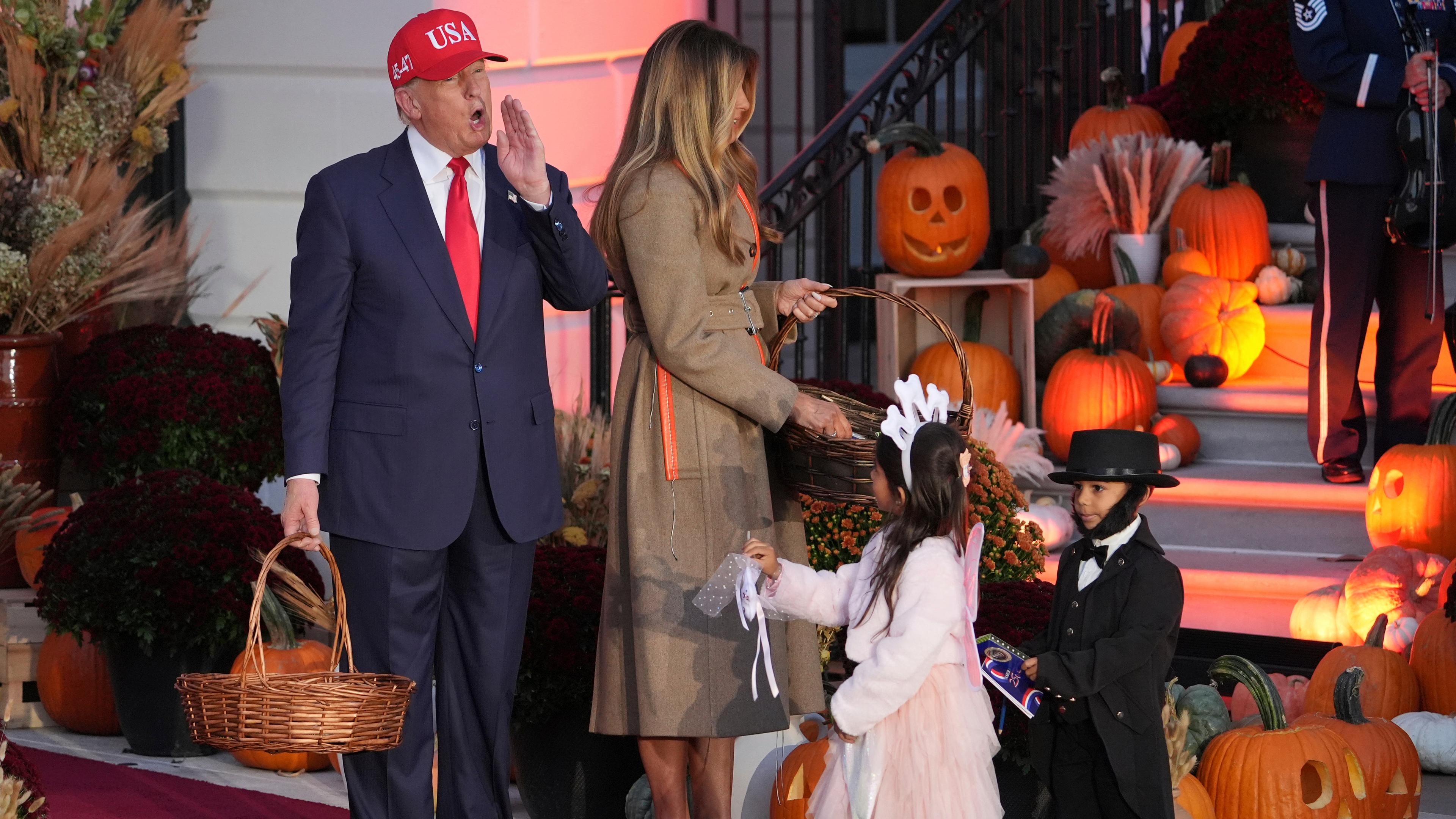 US-Präsident Donald Trump und First Lady Melania Trump verteilen Süßigkeiten an Kinder, die als Zahnfee und Abraham Lincoln verkleidet sind, während einer Halloween-Veranstaltung auf dem Südrasen des Weißen Hauses.