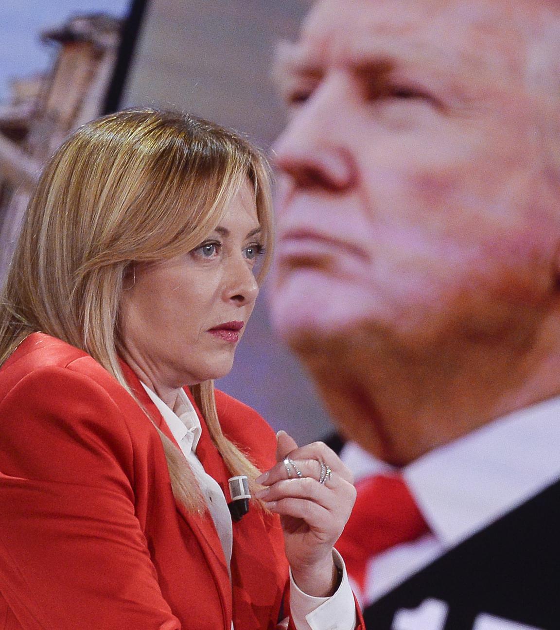 Giorgia Meloni sitzt in einer Talkshow. Im Hintergrund ist das Profil von Donald Trump zu sehen.