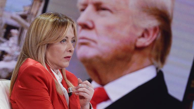 Giorgia Meloni sitzt in einer Talkshow. Im Hintergrund ist das Profil von Donald Trump zu sehen.