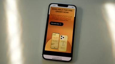 Ein iPhone am 16. Juni 2025 in Miami, Florida, die Website des Mobilfunkdienstes der Trump Organization und ein Smartphone mit der Marke Trump.