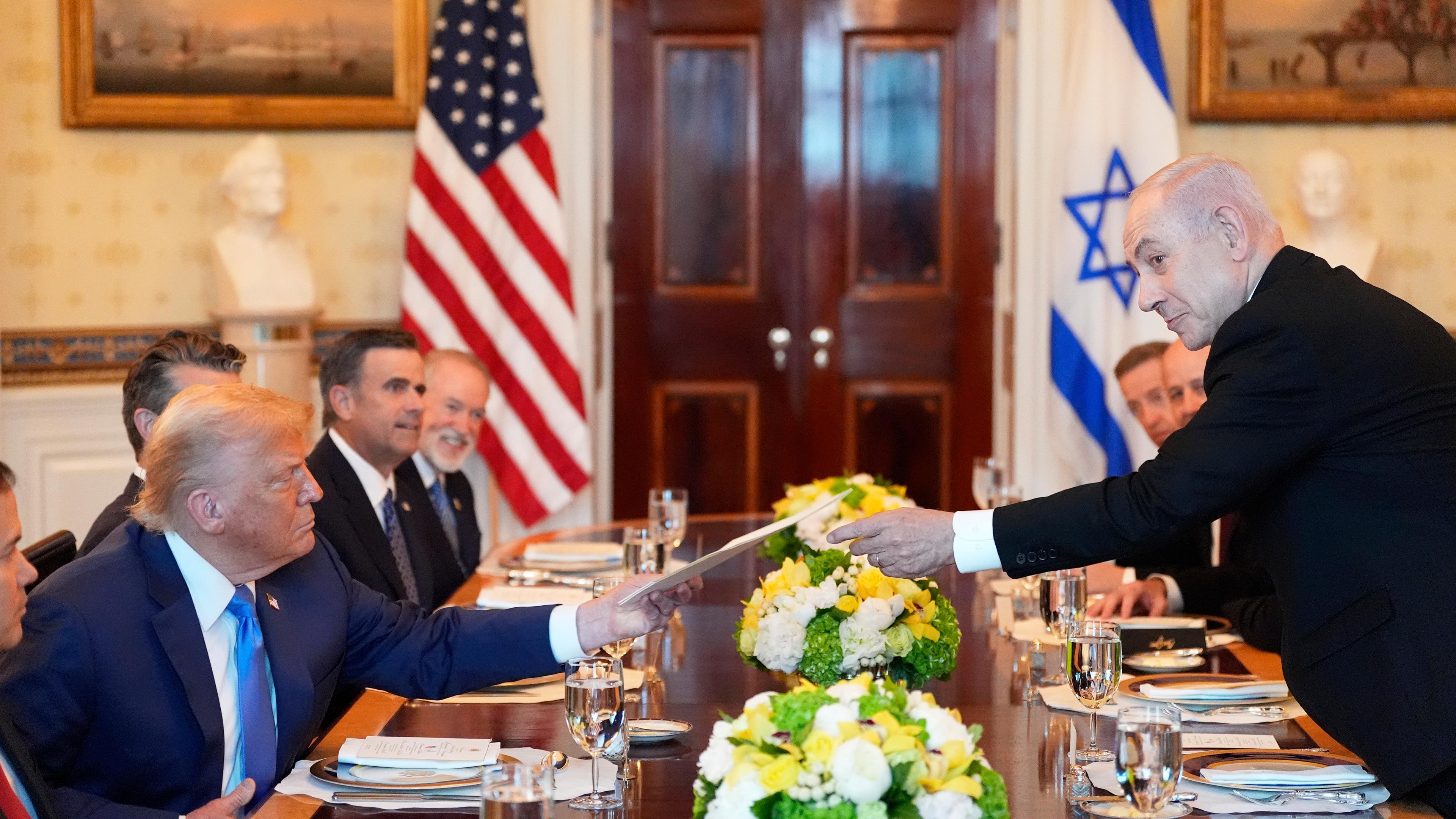 Benjamin Netanjahu (r), Ministerpräsident von Israel, überreicht US-Präsident Donald Trump eine Mappe während eines Treffens im Blue Room des Weißen Hauses in Washington.