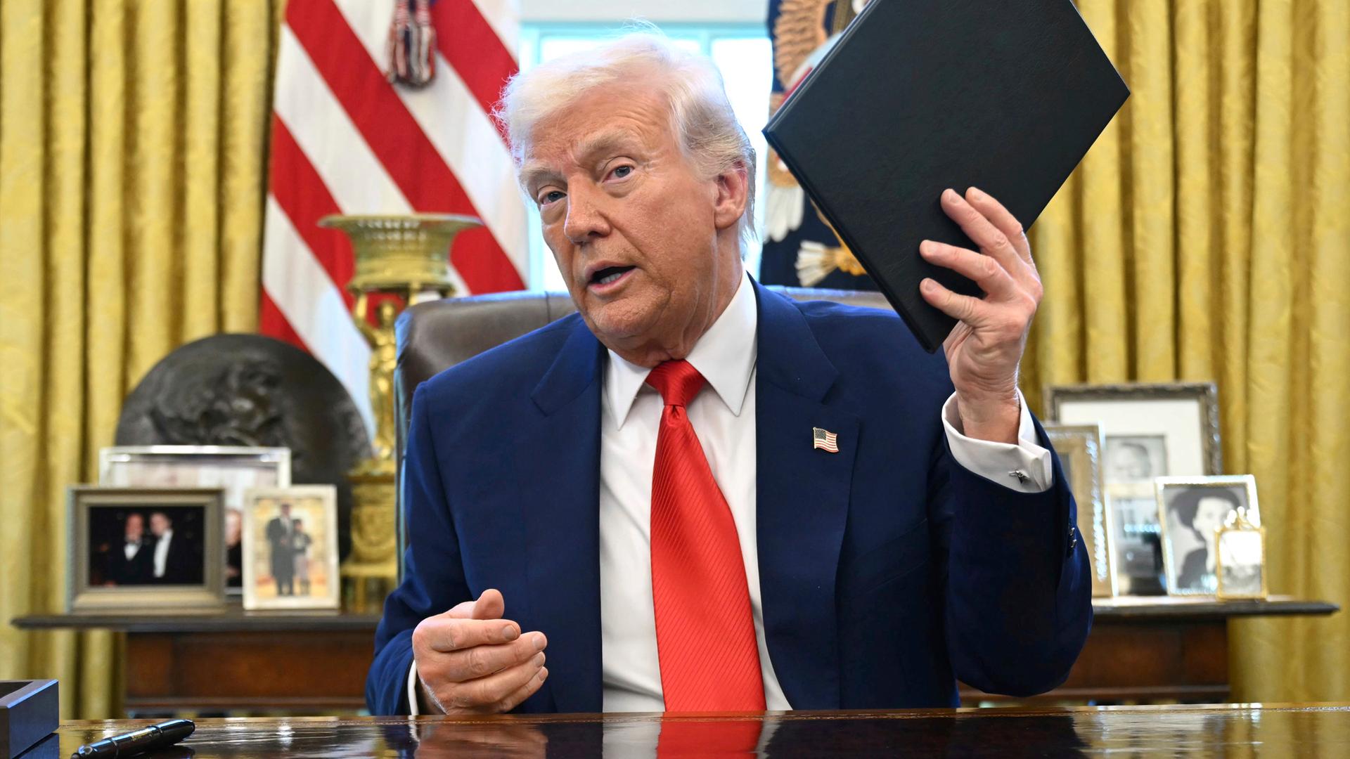 US-Präsident Trump mit Ordner in der Hand im Oval Office
