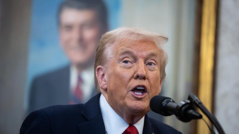 Trump spricht in ein Mikrofon.