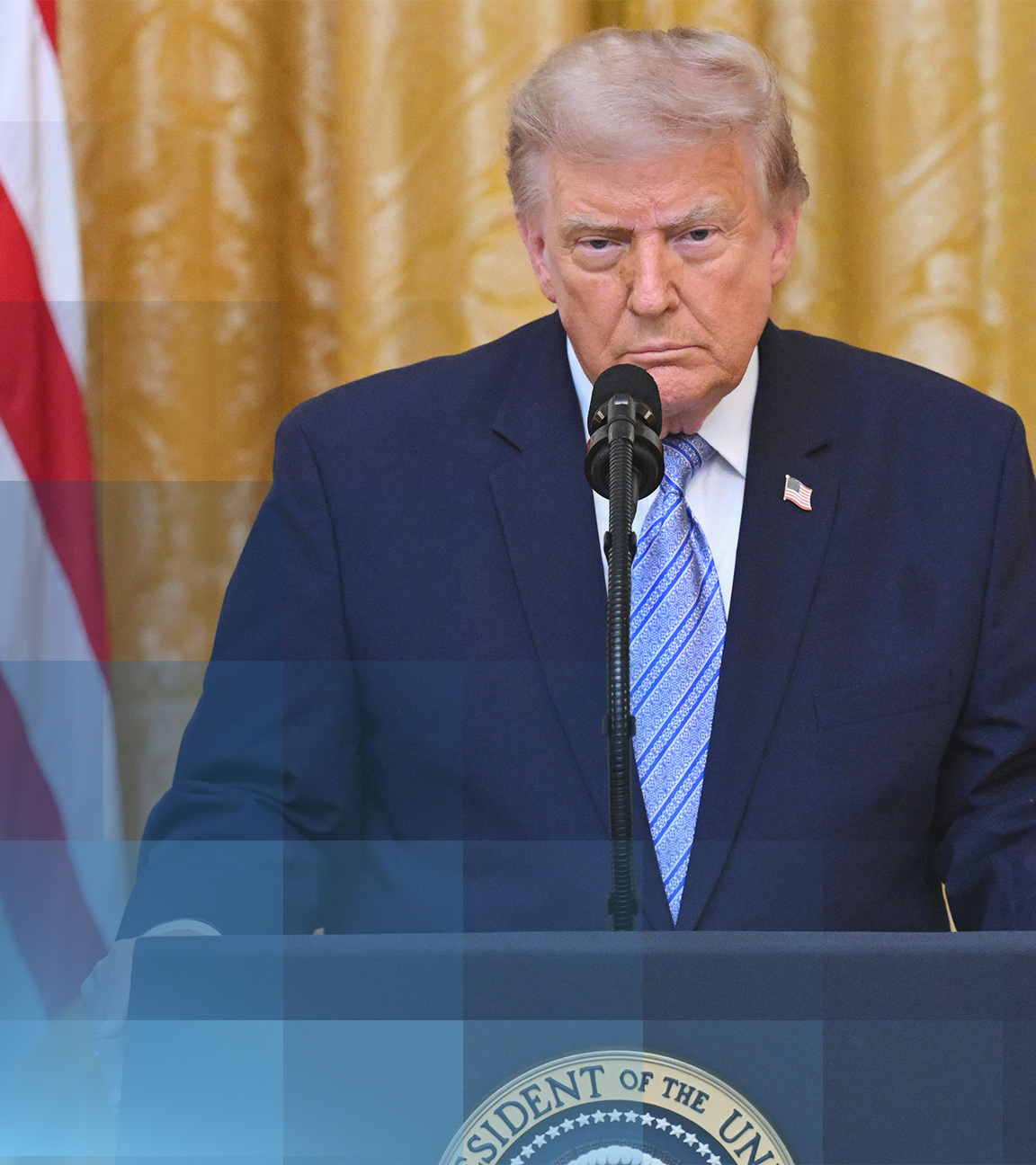 US-Präsident Donald Trump an seinem Rednerpult. Er guckt ernst und trägt einen dunkelblauen Anzug.