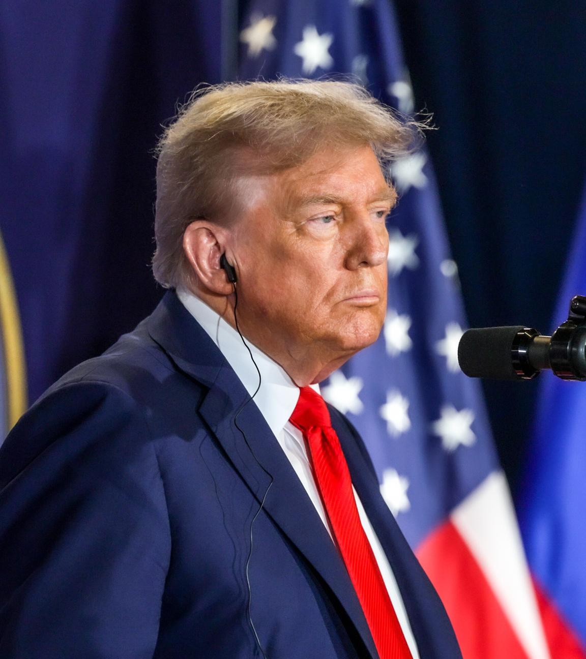 Zu sehen ist Donald Trump vor einem Mikrofon