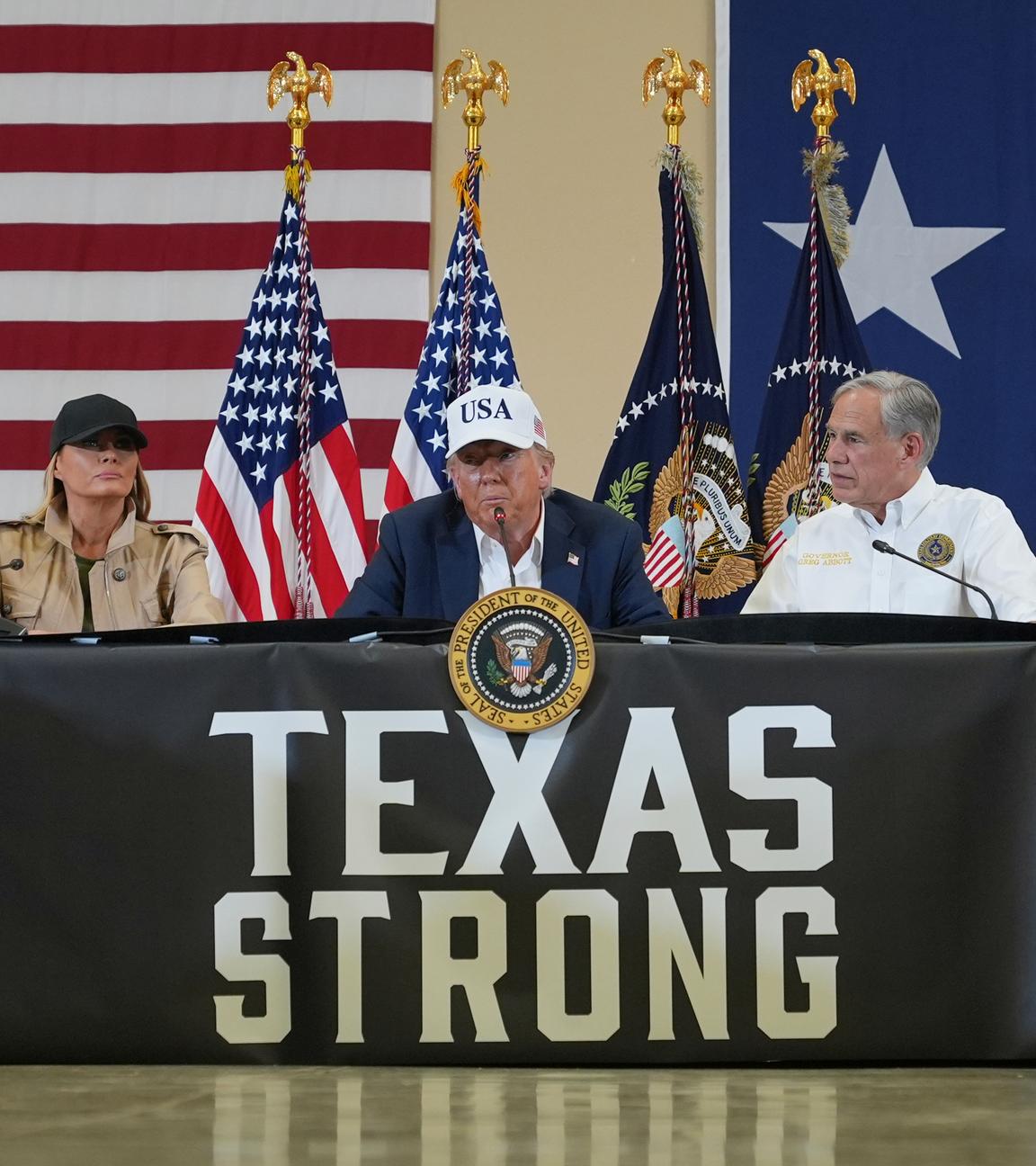 : US-Präsident Donald Trump spricht, während First Lady Melania Trump (l) und der texanische Gouverneur Greg Abbott während einer Diskussionsrunde mit Ersthelfern und lokalen Beamten im Hill Country Youth Event Center während einer Besichtigung von Hochwasserschäden zuhören.
