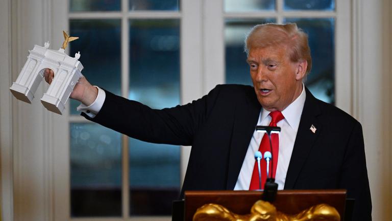 US-Präsident Donald Trump zeigt bei einem Abendessen für Spender, die zum Bau des neuen Ballsaals im Weißen Haus beigetragen haben, das Modell eines Triumphbogens. 
