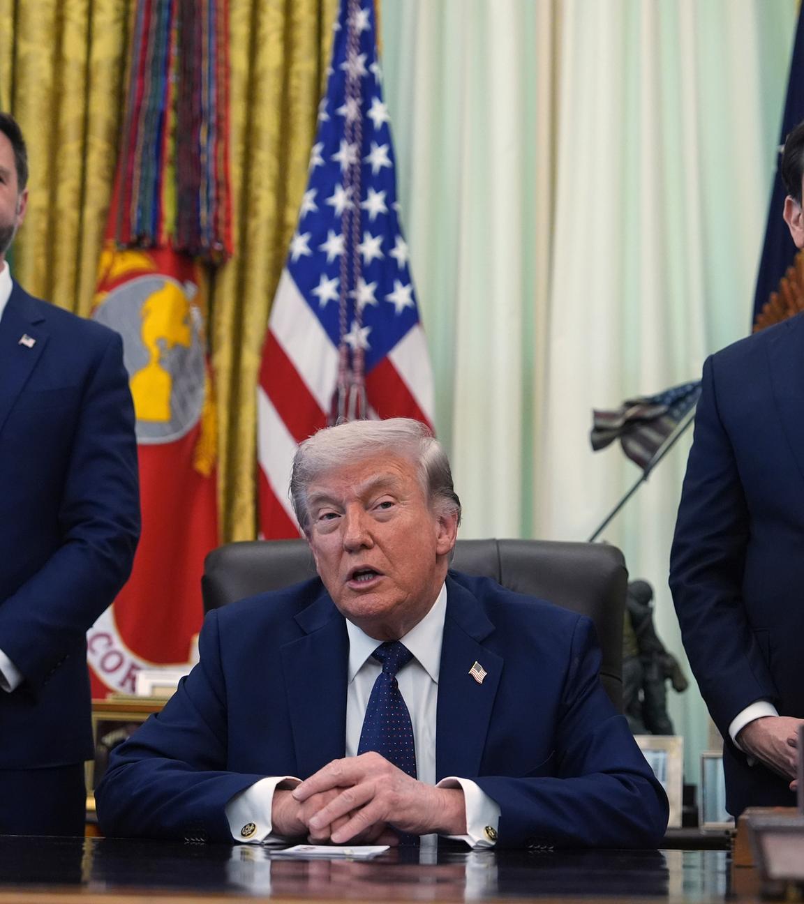 Donald Trump hält eine Rede, während seine Berater Marc Rubio und JD Vance hinter ihm stehen.