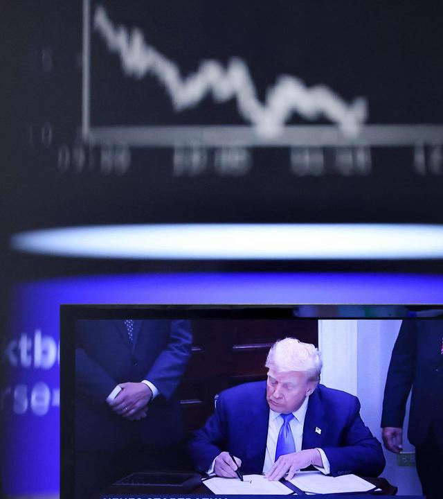 Ein Fernsehbildschirm mit US-Präsident Donald Trump ist am 1. August 2025 an der Börse in Frankfurt am Main zu sehen, im Hintergrund ist der Kursverlauf des deutschen Aktienindex DAX zu erkennen. 