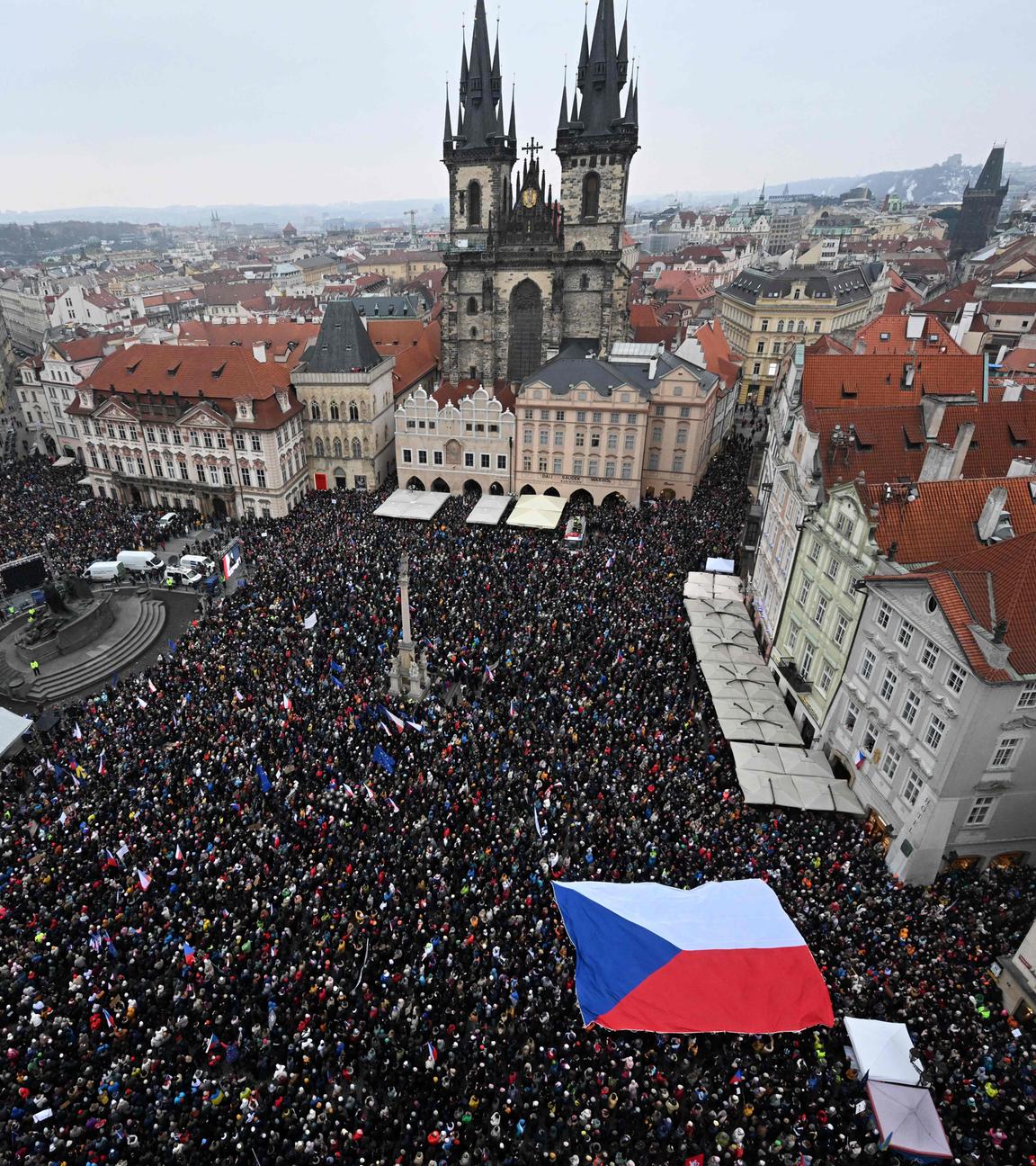 Luftaufnahme einer Menschenmasse aufe einem großen Platz vor einer Kirche, unten rechts ist eine große tschechische Flagge zu sehen.