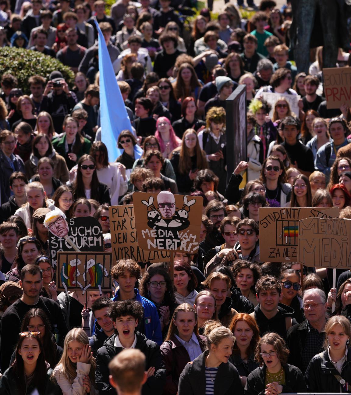 Junge Menschen protestieren dicht gedrängt auf einer Demonstration. Sie halten Schilder und Transparente hoch.
