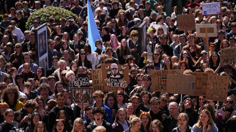 Junge Menschen protestieren dicht gedrängt auf einer Demonstration. Sie halten Schilder und Transparente hoch.