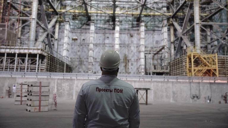Ein Überwachungsspezialist blickt auf das Schutzbauwerk über dem zerstörten Reaktor 4 in Tschernobyl.
