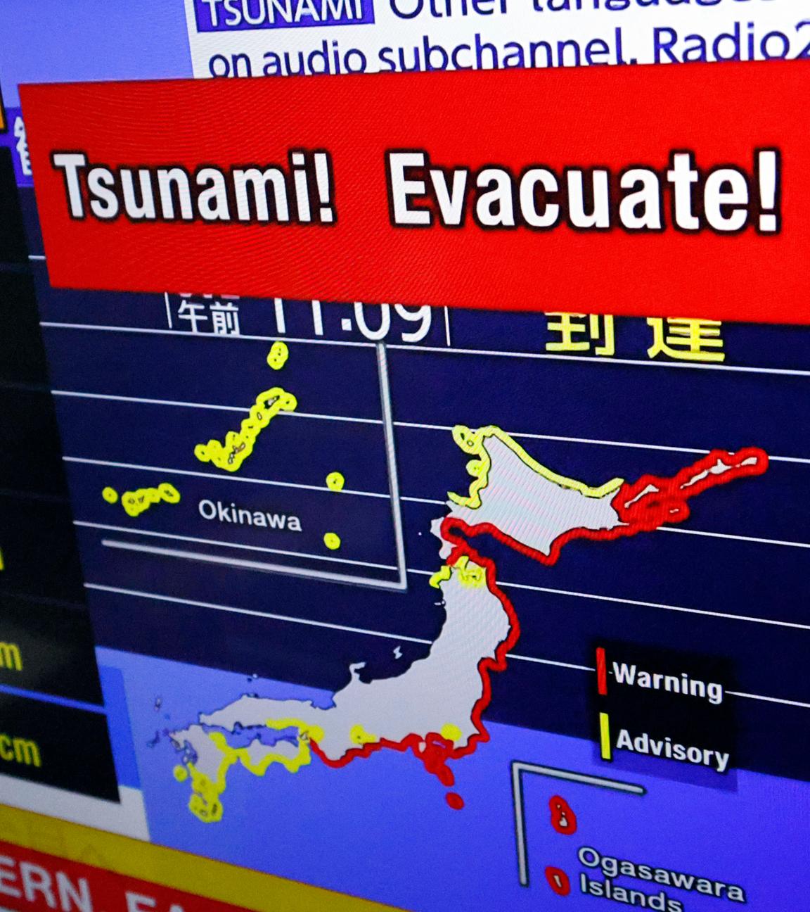 Ein Fernsehbildschirm zeigt eine Karte von Japan mit Tsunami Warnungen.