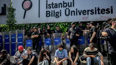 Türkei, Istanbul: Demonstranten sitzen während eines Protests vor der Bilgi-Universität vor Bereitschaftspolizisten, nachdem der türkische Präsident mitten im Studienjahr deren Schließung angeordnet hatte.