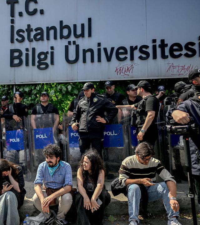 Türkei, Istanbul: Demonstranten sitzen während eines Protests vor der Bilgi-Universität vor Bereitschaftspolizisten, nachdem der türkische Präsident mitten im Studienjahr deren Schließung angeordnet hatte.