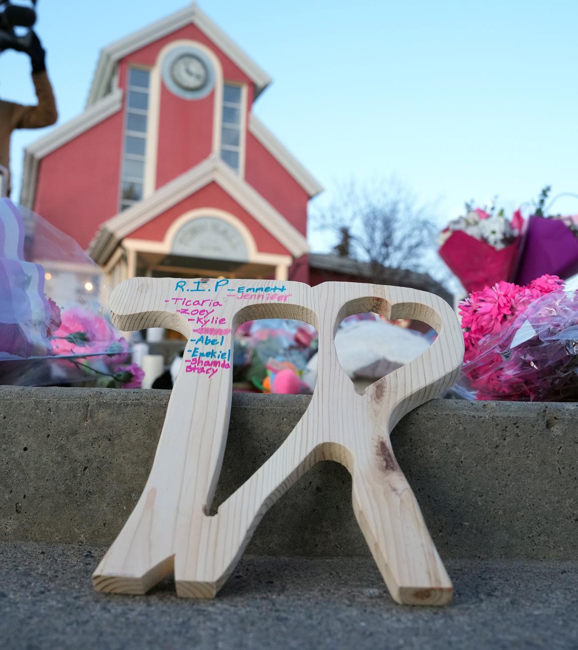 Bei einer Mahnwache für die Opfer eines Massenmordes in Tumbler Ridge wird ein Stück Holz gezeigt, in das „TR“ und die Namen der Opfer eingraviert sind.