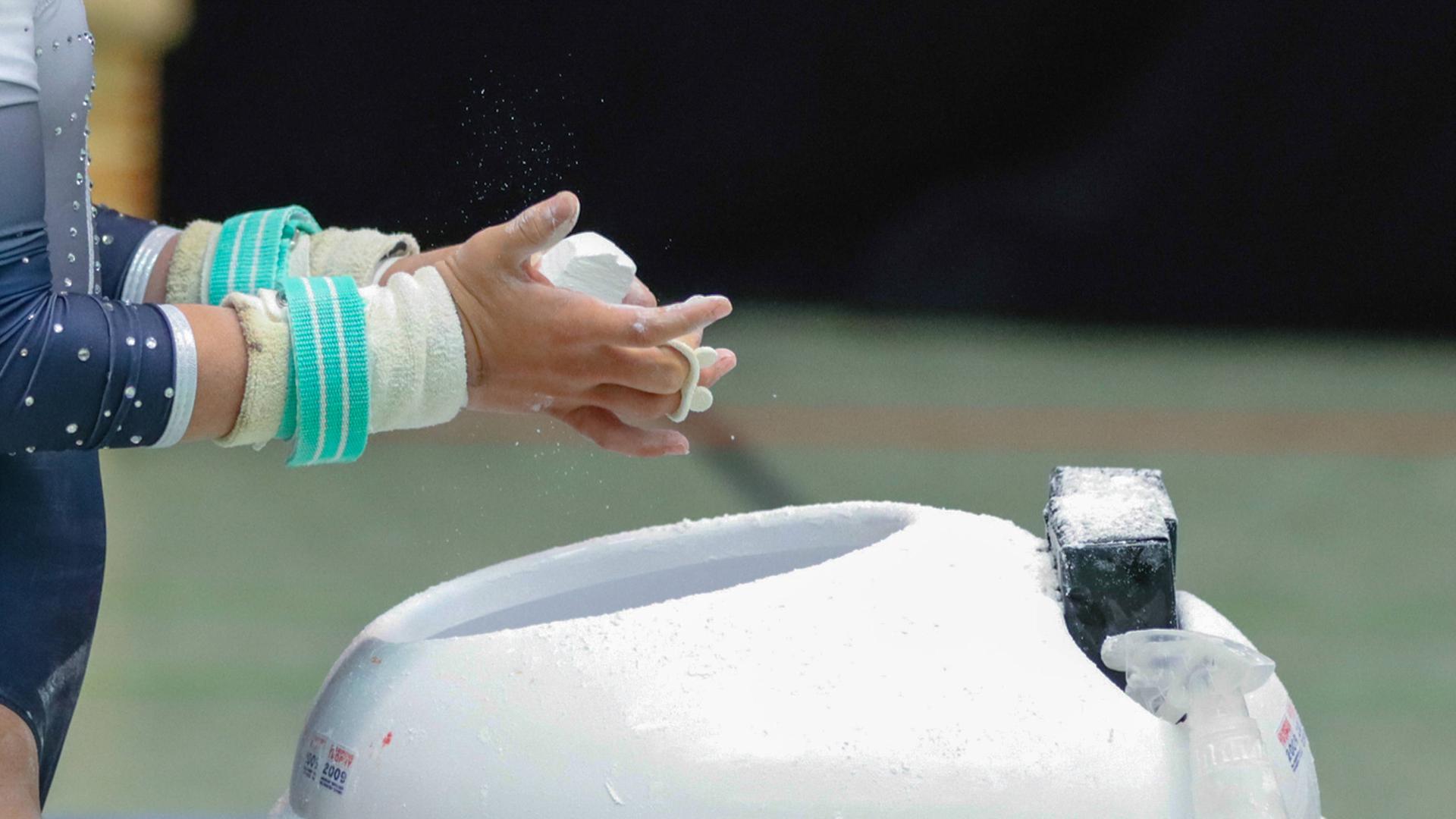 Turnerin reibt sich die Hände mit Kalk ein