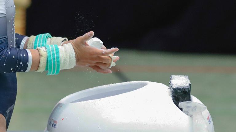 Turnerin reibt sich die Hände mit Kalk ein