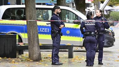 Einsatzkräfte der Polizei stehen an einem abgesperrten Bereich zu einem Schusswechsel in einer Fußgängerzone nahe dem Rathaus.