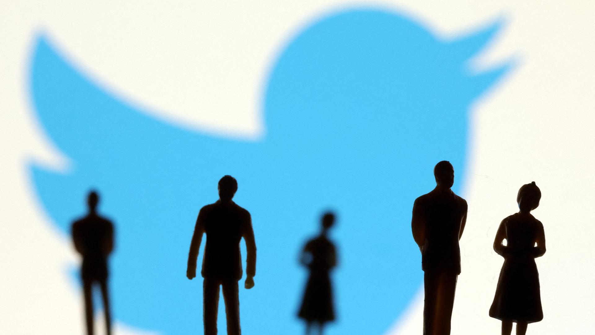 Vor dem Twitterlogo stehen schattige Figuren